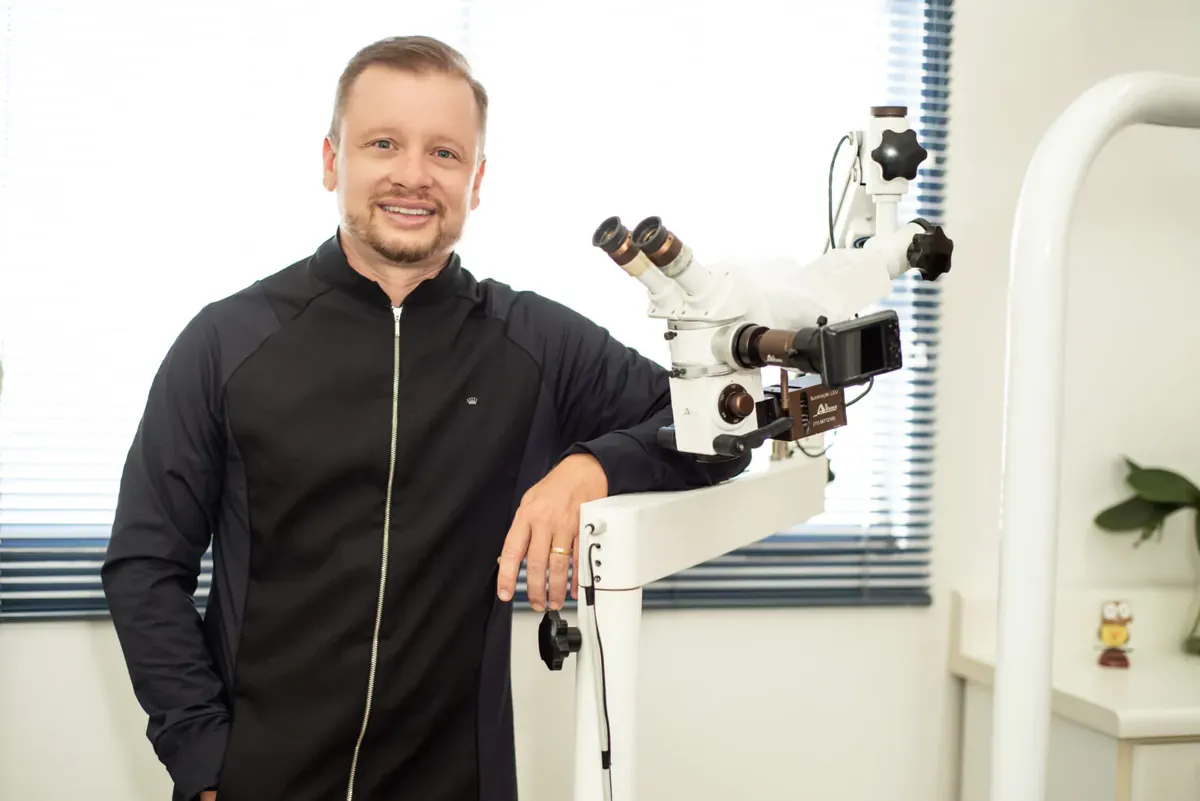 Dr. Rodrigo Vosiacki Rossi ao lado do microscópio operatório, em seu consultório em Limeira